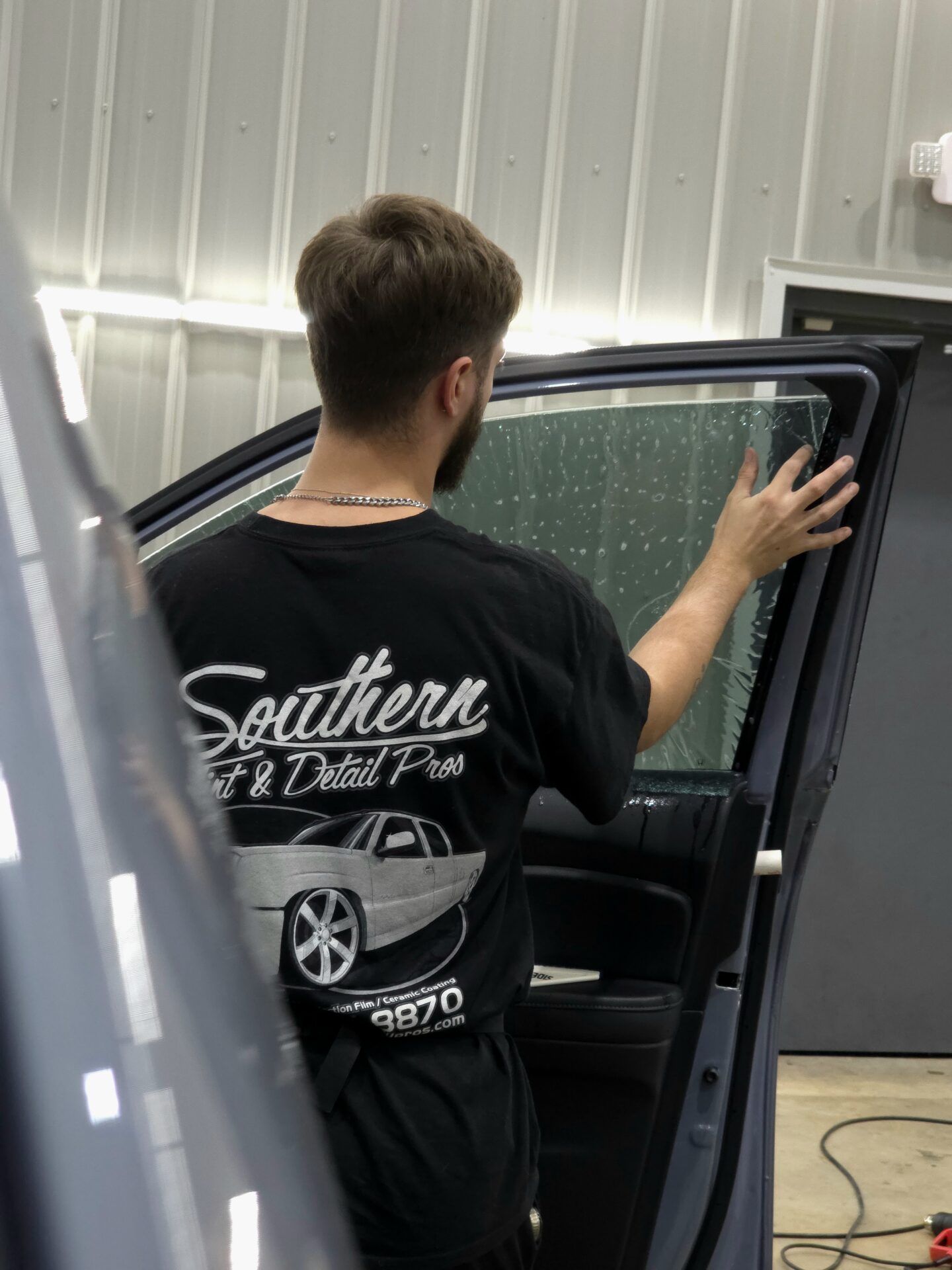 Technician installing automotive window tint at Southern Tint & Detail Pros in Baton Rouge