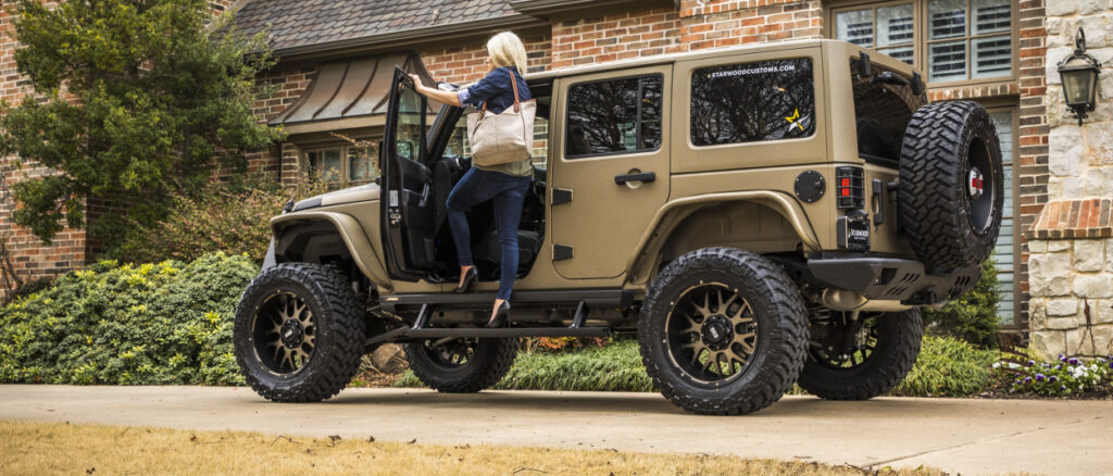 ARIES ActionTrac Power Steps on a tan Jeep Wrangler with a woman in heels stepping onto them